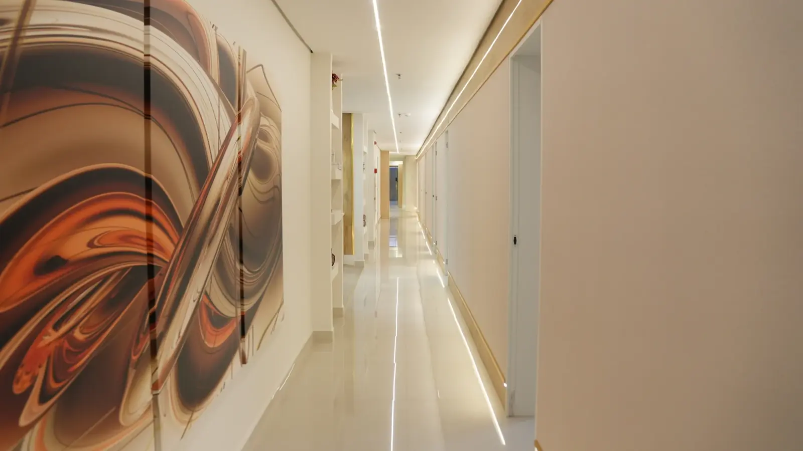 Corredor da Alphaview Concept com iluminação linear, arte contemporânea e acabamentos claros